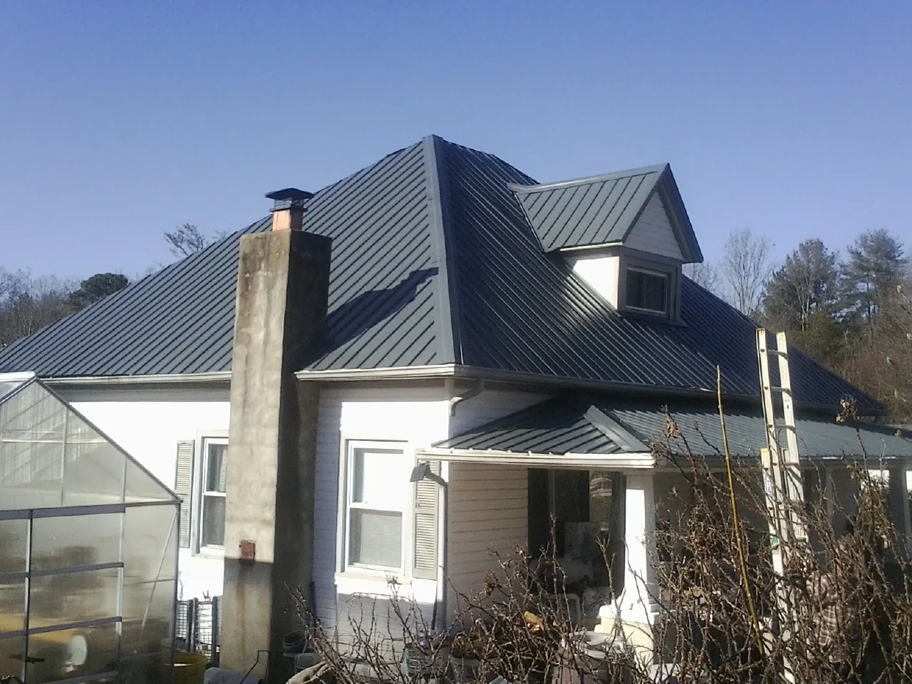 Dark blue standing seam metal roof on a white farmhouse with dormer — Slate & Tile Roof Repair by Roofing Brothers in Oregon