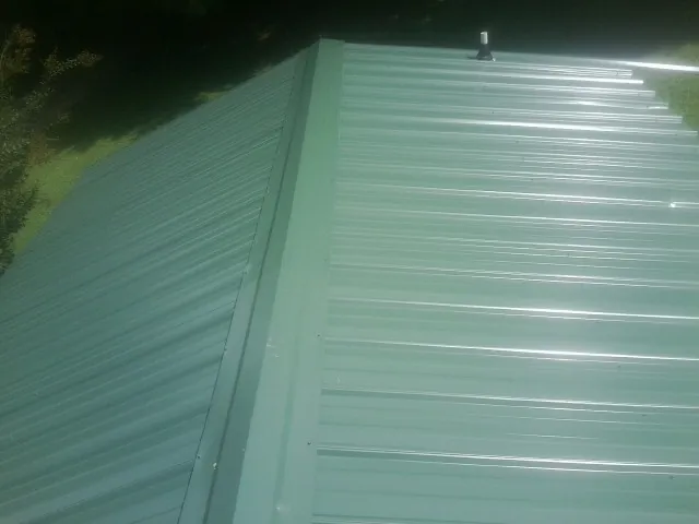 New green metal panels meeting at the ridge of a roof — Flat Roof Repair work by our crew in Oregon