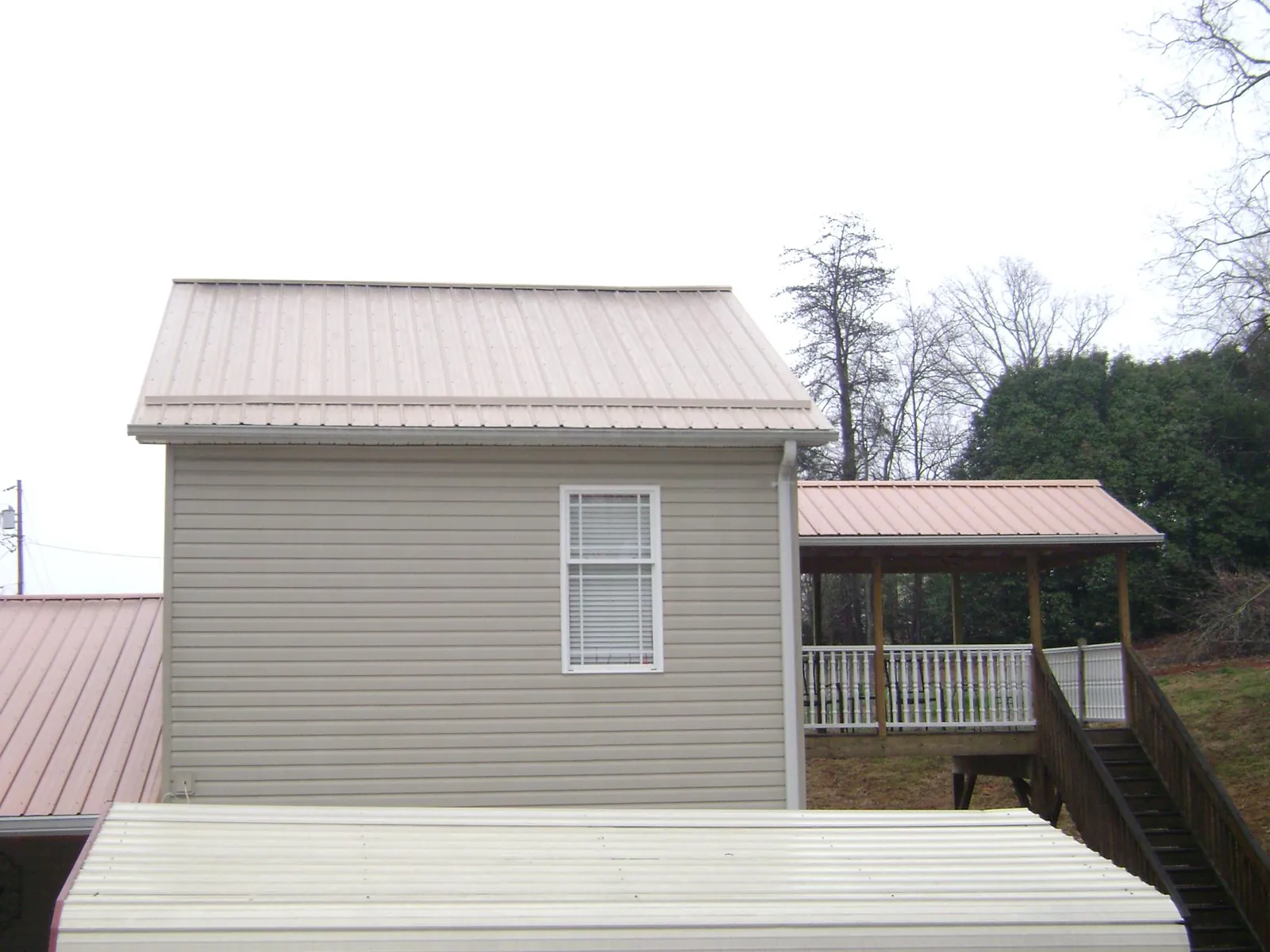 Tan metal roofs on a two story addition and attached porch, from a Roof Replacement job in Oregon